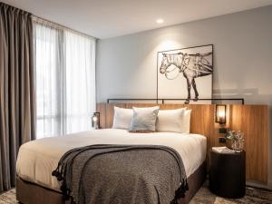 a bedroom with a bed with a horse picture on the wall at Mercure Sydney Rouse Hill in Kellyville