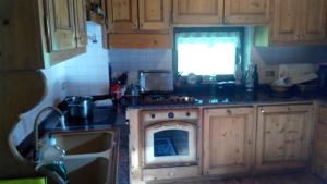 a kitchen with wooden cabinets and a stove top oven at Casa Alpina in Cencenighe