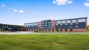 a large brick building with a grass field in front of it at Best Western Plus Portage Hotel and Suites in Portage