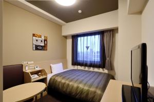 Hotel Route-Inn Kitakyushu-Wakamatsu Ekihigashi في كيتاكيوشو: غرفه فندقيه بسرير ونافذه