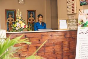 Una donna è in piedi dietro un bancone in una stanza di The Niche Bali a Legian