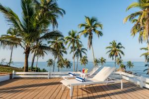 een terras met stoelen en palmbomen en de oceaan bij Casa Vagator in Vagator