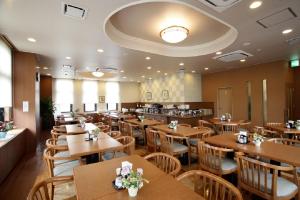 a dining room with wooden tables and chairs at Hotel Route-Inn Hamamatsu Nishi Inter in Hamamatsu