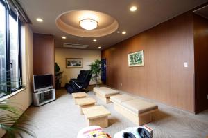 a waiting room with a couch and chairs and a tv at Hotel Route-Inn Hamamatsu Nishi Inter in Hamamatsu