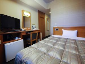a bedroom with a bed and a desk and a tv at Hotel Route-Inn Hamamatsu Eki Higashi in Hamamatsu