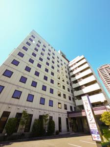 a tall white building with a sign in front of it at Hotel Route-Inn Hamamatsu Eki Higashi in Hamamatsu