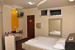 a small room with a bed and a mirror at Hotel Sol Centro (Adults Only) in Goiânia