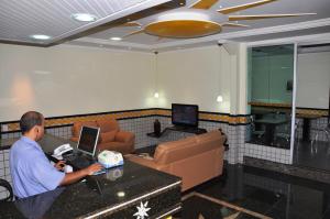a man working on a laptop in a room at Hotel Sol Centro (Adults Only) in Goiânia