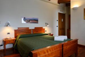 a bedroom with a wooden bed with a green bedspread at Hotel Rutiliano in Pienza