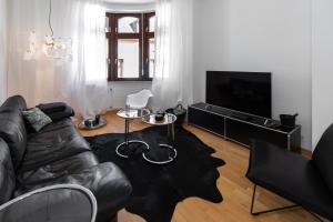 a living room with a leather couch and a television at Casa Augusta - Urban Living in Trier