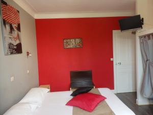 a bedroom with a red wall and a bed with a laptop at le relais des forêts in Blessac