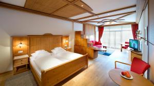 a bedroom with a large bed and a living room at Naturhotel Leitlhof in San Candido +69 photos
