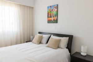 a bedroom with a bed with white sheets and pillows at Elysia Park in Paphos