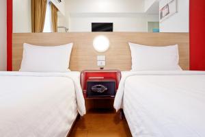 two beds with a red suitcase in a room at Red Planet Cagayan De Oro in Cagayan de Oro