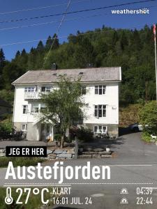 une maison blanche avec un panneau devant elle dans l'établissement Josygaard, à Austefjorden