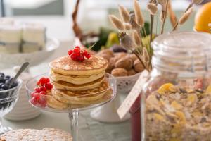 un tavolo ricoperto da una pila di pancake e frutta di B&B Di Charme Le Contrade a SantʼArcangelo di Romagna