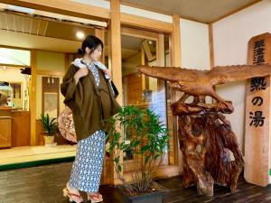 una mujer de pie junto a una estatua en un edificio en Kirishimaya Ryokan, en Kusatsu