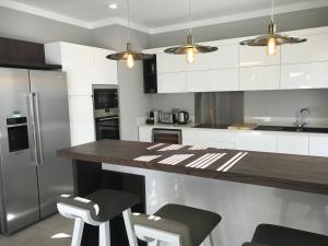 a kitchen with white cabinets and a counter with stools at Luxury Villas at Royal Park in Balaclava