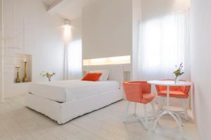 a white bedroom with a white bed and a table at B&B Di Charme Le Contrade in Santarcangelo di Romagna