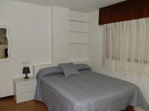 a white bedroom with a bed and a window at Apartamentos Turisticos Beatriz in Perillo