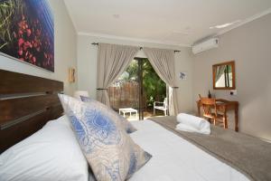 1 dormitorio con 2 camas con sábanas blancas y ventana en Cuckoos Nest Guest House, en Louis Trichardt