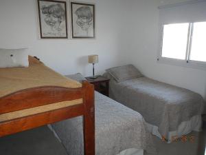 sypialnia z 2 łóżkami pojedynczymi i oknem w obiekcie Duplex Barrancas w mieście Puerto Madryn