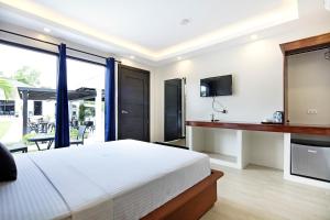 a bedroom with a bed and a tv and a balcony at OHANA, Panglao Resort. in Panglao