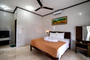 1 dormitorio con 1 cama y ventilador de techo en Megacahya Bungalow, en Nusa Lembongan