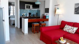 a living room with a red couch and a kitchen at Aqua Apt Sunrise & Sea Views in Costa Teguise