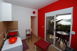 a kitchen with red walls and a balcony with a table at Apartments Sergej in Sutomore