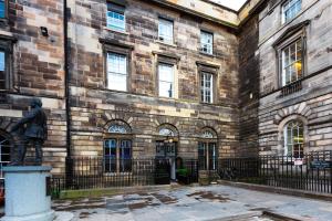 een standbeeld van een man voor een bakstenen gebouw bij CoDE Pod – The CoURT - Edinburgh in Edinburgh