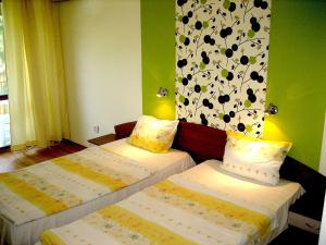 two beds in a room with a flower pattern on the wall at Hotel Valena in Kiten