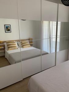 1 dormitorio con 2 camas y pared de espejo en Appartamento Acquamarina, en San Benedetto del Tronto