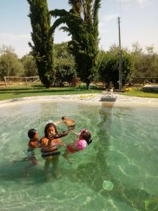 3 enfants jouant dans une piscine dans l'établissement Elisabeth House, à Lucignano