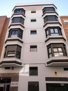 een hoog wit gebouw met zwarte ramen bij Apartamentos Legazpi in Albacete