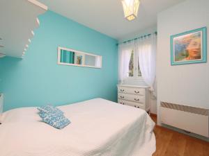 Dormitorio azul con cama y ventana en Apartment Le Garden by Interhome, en Cabourg