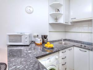 uma cozinha branca com um lavatório e um micro-ondas em Apartment Palmiers I-7 by Interhome em Llançà