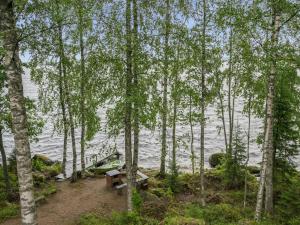 a picnic table and a bench in the woods by the water at Holiday Home Laitamökki by Interhome in Tasapää