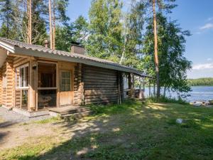 een blokhut met een veranda en een meer bij Holiday Home Lemmenmaja by Interhome in Paatela