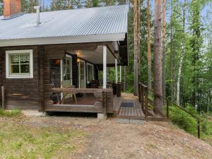 a small cabin with a deck in the woods at Holiday Home Keskimökki by Interhome in Tasapää