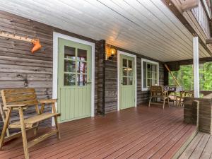a wooden porch with a bench and a table at Holiday Home Keskimökki by Interhome in Tasapää