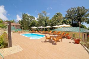a patio with tables and chairs and a swimming pool at The Palm Seychelles in Bel Ombre