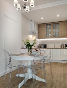 a kitchen with a white table and chairs at Prestige Apartment Słupsk in Słupsk