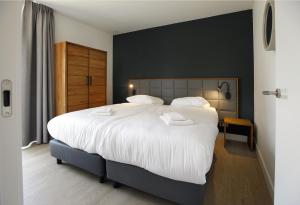 a bedroom with a large bed with white sheets at Landgoed Bergvliet in Oosterhout