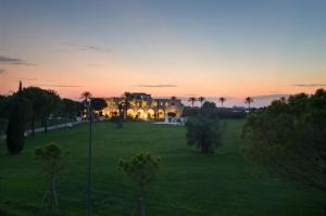 a house in a field with a sunset in the background at Masseria La Baronessa Resort in Tuglie