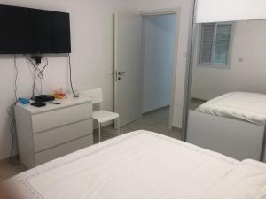 a white bedroom with a bed and a mirror at The Urban Apartment in Haifa