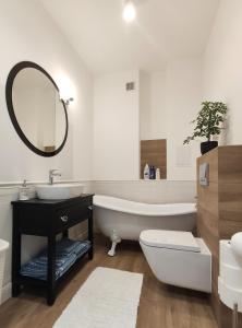 a bathroom with a tub and a sink and a mirror at Prestige Apartment Słupsk in Słupsk