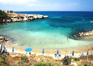 - une plage avec des parasols bleus et des personnes dans l'eau dans l'établissement Phaedrus Living: Seaside Luxury Villa Anafi, à Paralímni
