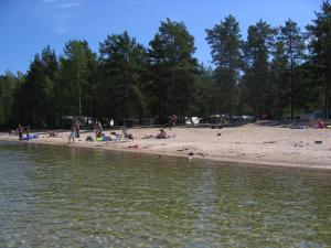 un grupo de personas en una playa cerca del agua en Ruoke Holiday Village, en Kesälahti