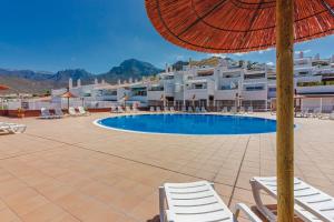 ein Resort mit einem Pool mit Stühlen und einem Sonnenschirm in der Unterkunft Apartment with ocean view in Costa Adeje in Adeje